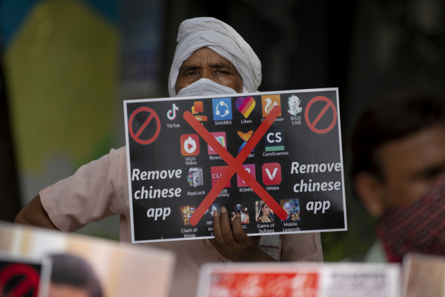 중국과 히말라야에서 국경 분쟁이 일어난 직후인 2020년 8월 인도 수도 뉴델리에서 열린 반중 집회에서 한 시민이 중국산 앱을 스마트폰에서 삭제할 것을 촉구하는 플래카드를 들고 있다. AP연합뉴스