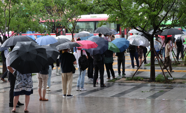 수도권 폭우가 계속된 9일 오후 서울 종로구 세종로사거리 인근에서 퇴근길 시민들이 버스를 기다리고 있다. 연합뉴스