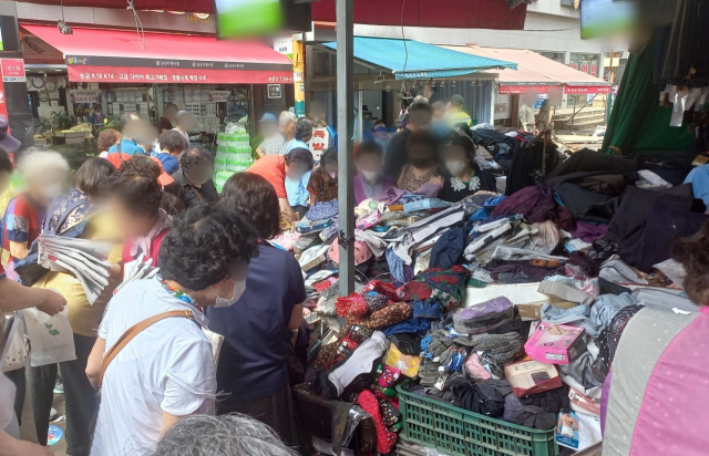 시민들이 11일 서울 동작구 사당동 남성사계시장의 한 옷가게 앞에서 폭우로 젖은 상품들을 구입하기 위해 살펴보고 있다. 이건율 기자