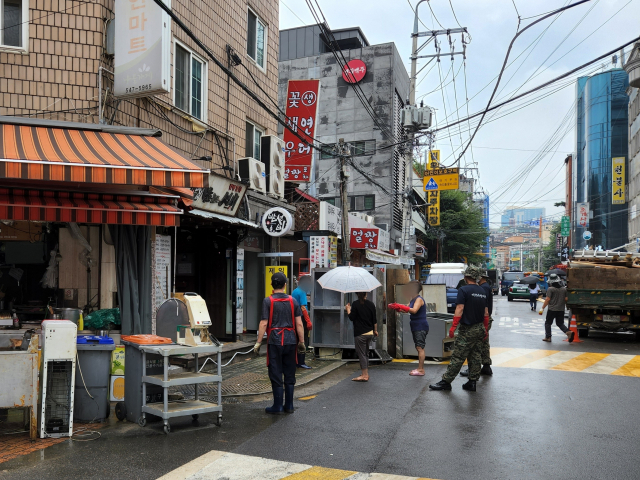 서울 강남구 논현동 영동전통시장 내 상점 직원들이 11일 오후 군인들과 함께 젖은 집기류를 가게 밖으로 꺼내고 있다. 김남명 기자