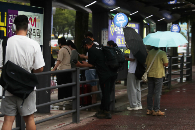 11일 오후 광주 서구 광천동에서 시민들이 우산을 쓴 채 택시를 기다리고 있다. 수도권에 머물며 많은 비를 뿌린 정체전선이 남부지방으로 향하면서 12일 오전까지 광주와 전남에 최고 100㎜의 비가 내릴 예정이다. 광주=연합뉴스
