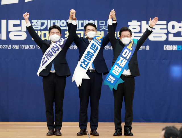 13일 부산항 국제컨벤션센터에서 열린 더불어민주당 당 대표·최고위원 후보 합동연설회에서 강훈식(왼쪽부터), 박용진, 이재명 당 대표 후보가 손을 맞잡고 인사하고 있다./연합뉴스