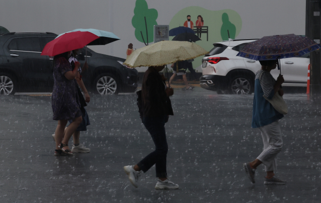 서울 지역에 오후부터 비가 내린 19일 서울 종로구 세종문화회관 앞에서 우산을 쓴 시민들이 오가고 있다. 연합뉴스