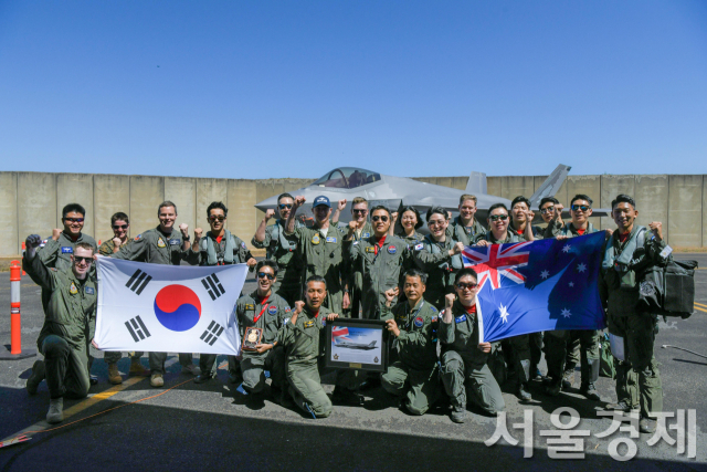 한국과 호주 공군 조종사와 훈련단장, 지원요원들이 2022년 8월 24일(현지시간) 호주 다윈기지에서 연합 편대비행 및 공중급유훈련을 마친 뒤 서로의 국기를 나눠들며 파이팅을 외치고 있다. 사진제공=공군