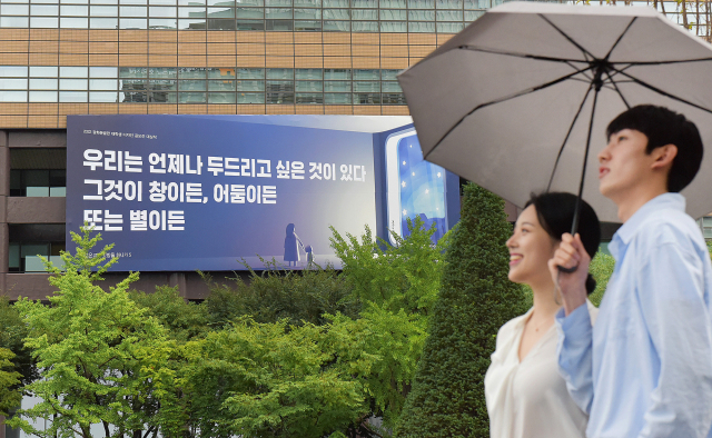 시민들이 29일 교보생명 광화문글판 ‘가을편’이 내걸린 광화문 교보생명빌딩 주변을 걷고 있다. 이번 문안은 강은교 시인의 시 ‘빗방울 하나가 5’에서 가져왔다. 아무리 작은 존재라도 능동적인 주체로서 희망을 향해 나아가고 싶은 열망이 있음을 잊지 말자는 의미를 담았다. 사진 제공=교보생명