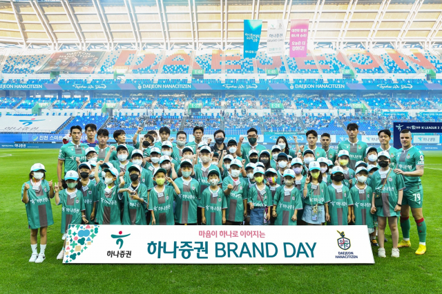 27일 하나증권브랜드데이를 맞아 축구경기 전 대전하나시티즌 선수들이 임직원 자녀들과 함께 기념촬영을 하고 있다. 사진제공=하나증권