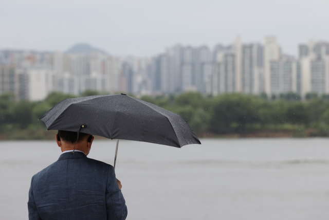 전국 곳곳에 비가 내린 29일 서울 여의도 물빛광장분수 인근에서 우산을 쓴 시민이 한강을 바라보고 있다. 연합뉴스