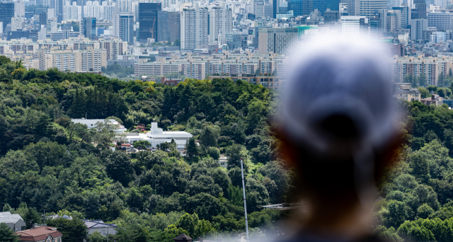 지난 24일 오전 서울 남산에서 바라본 서울 용산구 한남동 대통령 새 관저를 시민이 바라보고 있다. 윤석열 대통령 내외는 이달 말 즈음 관저의 리모델링이 완료되면 입주할 예정이다. 연합뉴스