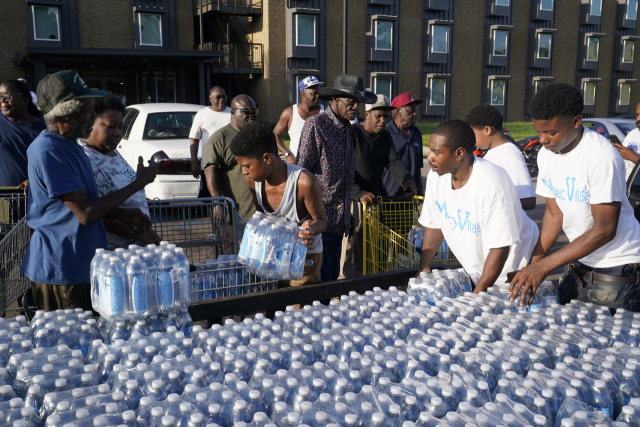 1일(현지 시간) 미국 미시시피주 주도인 잭슨시 주민들이 식수를 얻기 위해 생수 배급 트럭 앞에 모여 있다.AP연합뉴스