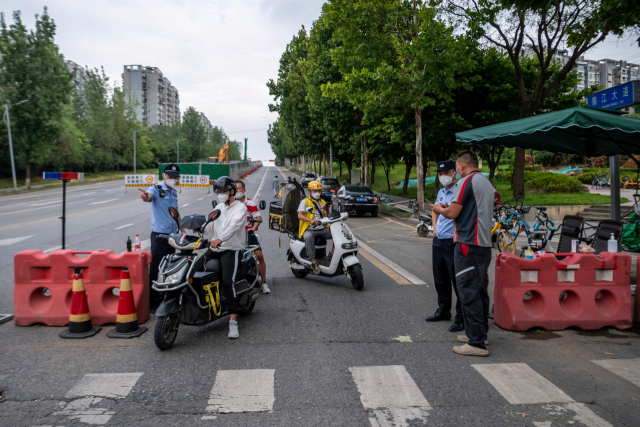 1일 코로나19 봉쇄 조처가 내려진 중국 쓰촨성 성도 청두에서 경찰들이 행인들의 정보를 확인하고 있다./연합뉴스