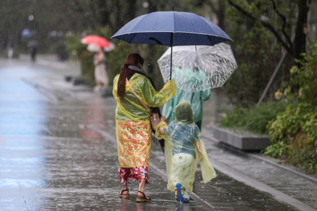 제11호 태풍 힌남노 영향으로 큰 비가 내린 5일 한 학부모가 자녀의 손을 잡고 하교하고 있다. 연합뉴스