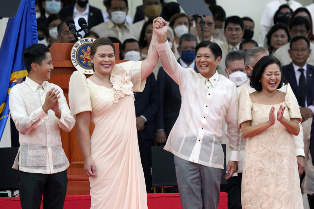 6월 30일(현지 시간) 페르디난드 마르코스 주니어 필리핀 대통령(중앙 오른쪽)과 사라 두테르테 필리핀 부통령이 손을 잡고 취임식에서 인사를 하고 있다. 필리핀의 독재자 고(故) 페르디난드 마르코스의 아들이 17대 대통령에 취임하며 악명 높은 독재자 가문이 36년 만에 다시 권력을 잡게 됐다.AP연합뉴스