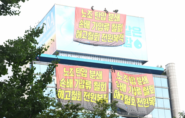 하이트진로 본사 옥상 광고탑을 점거한 민주노총 공공운수노조 화물연대 조합원들이 지난달 18일 서울 강남구 청담동 하이트진로 본사 앞에서 열린 '고공농성 승리 결의대회'를 지켜보고 있다.오승현 기자
