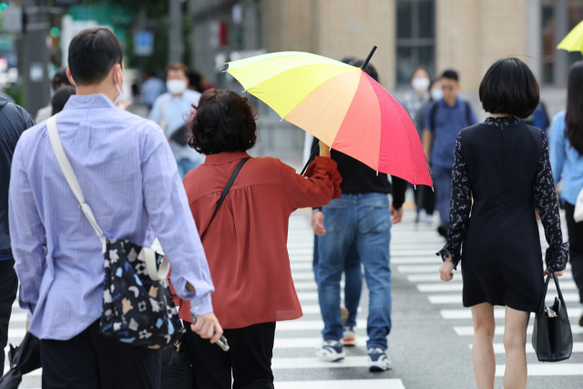 6일 서울 종로구 광화문광장에서 시민이 우산을 접고 있다. 연합뉴스