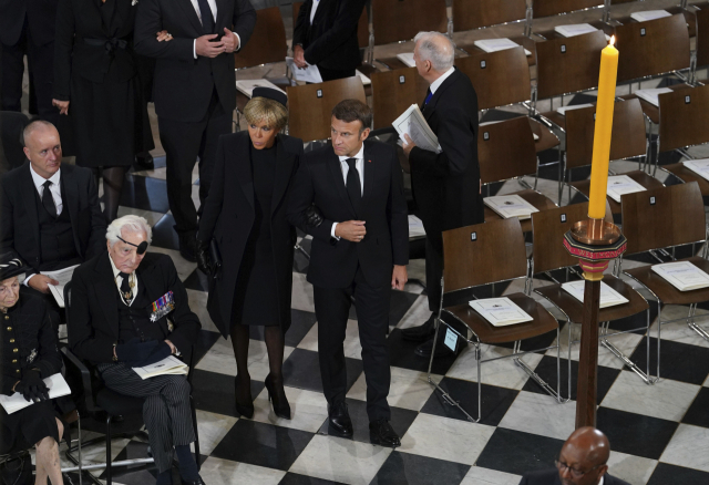 에마뉘엘 마크롱(앞줄 오른쪽) 프랑스 대통령과 브리지트 여사가 19일(현지 시간) 엘리자베스2세 여왕의 장례식이 열리는 웨스트민스터 사원에 입장하고 있다. AP연합뉴스