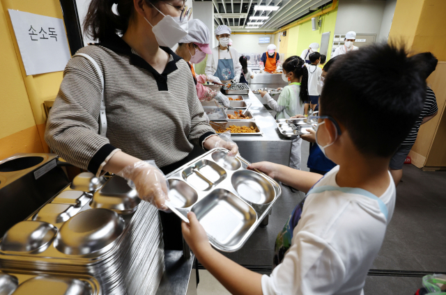 지난달 26일 서울 영등포구 여의도 윤중초등학교에서 학생들이 방역 수칙을 준수하며 점심 배식을 받고 있다. 연합뉴스