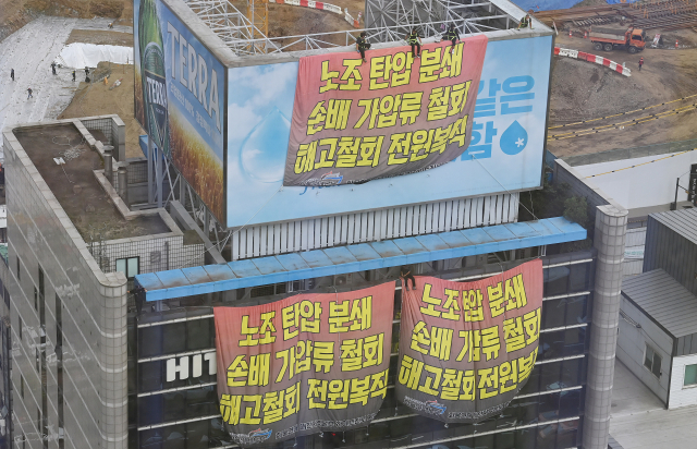 지난달 18일 하이트진로 본사 옥상 광고탑을 점거한 민주노총 공공운수노조 화물연대 조합원들이 서울 강남구 청담동 하이트진로 본사 앞에서 열린 '고공농성 승리 결의대회'를 지켜보고 있다./오승현 기자
