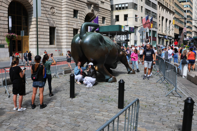 월가의 상징인 뉴욕 맨해튼 돌진하는 황소(Charging bull)상을 배경으로 관광객들이 사진을 찍고 있다. AFP연합뉴스