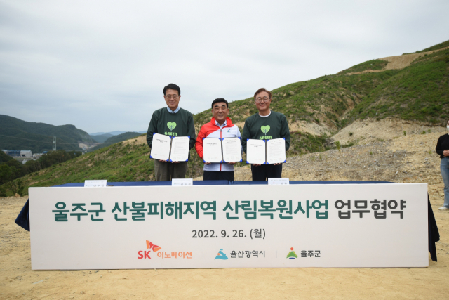 26일 울산 울주군 대복리 산불 피해 현장에서 열린 ‘SK 울산 행복의 숲’ 조성을 위한 업무협약식에서 이순걸(왼쪽부터) 울주군수, 김두겸 울산시장, 김준 SK이노베이션 부회장이 협약서를 들어보이고 있다. 사진 제공=SK이노베이션