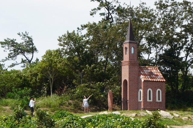 딴섬에 있는 12번 예배당 가롯 유다의 ‘지혜의 집’을 배경으로 사진을 찍고 있다.