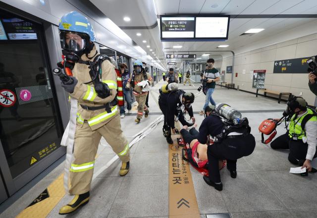 소방관들과 공항철도 직원들이 27일 서울 강서구 마곡나루역에서 열린 '2022년 재난대응 안전한국훈련' 시범훈련에서 화재진압 및 인명구조 훈련을 하고 있다. 연합뉴스