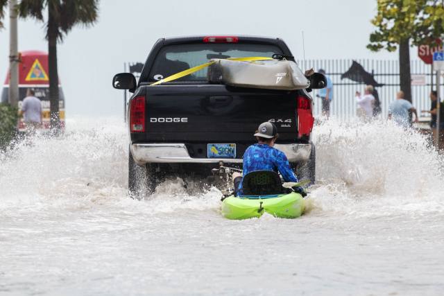 28일(현지시간) 미국 플로리다주 키웨스트의 서던모스트포인트 부이 근처에서 한 시민이 트럭에 묶인 카약에 탄 채 허리케인 '이언'(Ian)으로 발생한 홍수로 물이 불어난 거리를 달리고 있다. AP연합뉴스