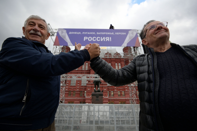우크라이나 4개 주의 러시아 병합을 축하하기 위해 29일(현지 시간) 모스크바 붉은광장 앞에 설치된 무대에서 시민들이 병합을 자축하고 있다. 무대에 걸린 플래카드에는 '도네츠크, 루한스크, 자포리자, 헤르손-러시아!'라고 적혀 있다. AFP연합뉴스