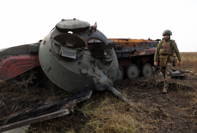 지난달28일(현지시간) 우크라이나 도네츠크 지방에 있는 최전선에서 파괴된 러시아 전차 주위를 한 우크라이나 군인이 지나치고 있다. /연합뉴스