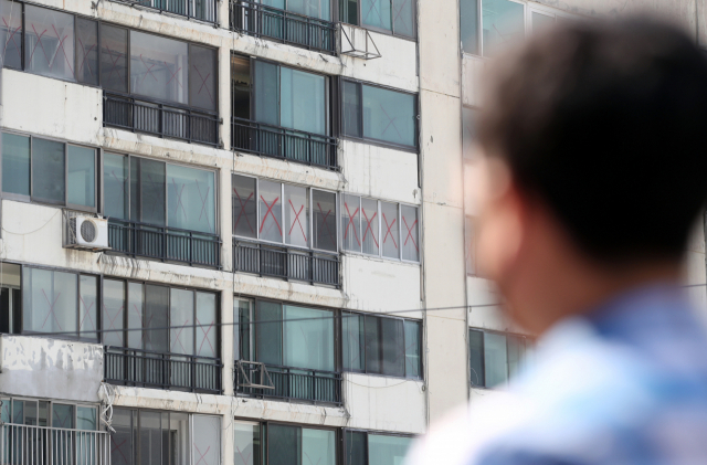 한 시민이 재건축으로 이주가 진행 중인 아파트 단지를 바라보고 있다./연합뉴스
