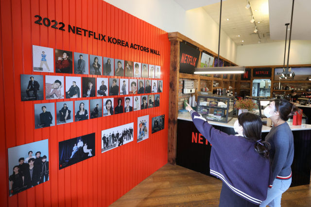 부산 해운대구 우동 KNN타워 내 한 카페에 마련된 넷플릭스 사랑방에서 방문객들이 전시된 사진들을 보고 있다. 연합뉴스