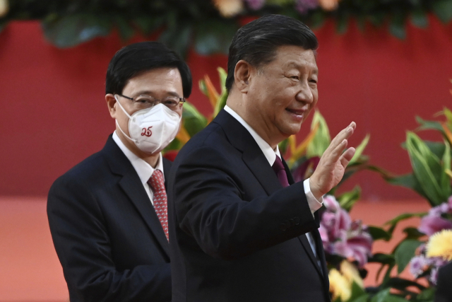시진핑(오른쪽) 중국 국가주석이 홍콩 주권 반환 25주년인 7월 1일 홍콩 컨벤션센터에서 열린 존 리 신임 홍콩 행정장관의 취임식을 마친 뒤 리 행정장관과 나란히 걸어가며 손을 들어 인사하고 있다. 연합뉴스