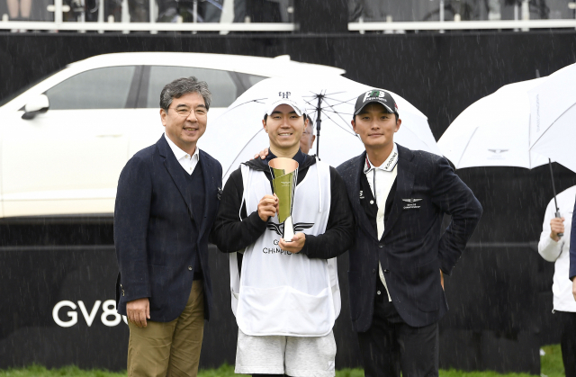 장재훈(왼쪽 첫번쨰) 제네시스 사장이 ‘2022 제네시스 챔피언십’에서 우승한 김영수(왼쪽 세번째) 선수의 캐디 김재민 씨에게 별도로 마련한 트로피를 전달한 후 기념촬영을 하고 있다. 사진제공=현대차그룹