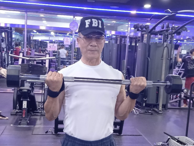 70세 헬스 트레이너 강철진 씨가 50㎏짜리 역기로 팔 근육 단련 운동을 하고 있다. 강 씨는 헬스 관련 동영상 100여 개를 만들어 공개하는 등 유튜버로도 활동하고 있다.