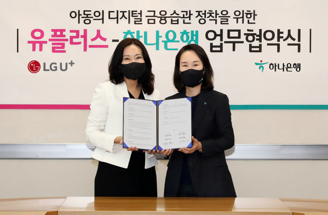 정혜윤(왼쪽) LG유플러스 마케팅그룹장과 김소정 하나은행 디지털경험본부 부행장이 업무협약서를 들어보이고 있다. 사진제공=LG유플러스