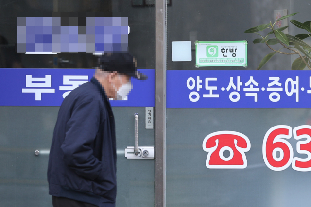 서울의 한 시민이 공인중개소 앞을 지나가고 있다. 연합뉴스