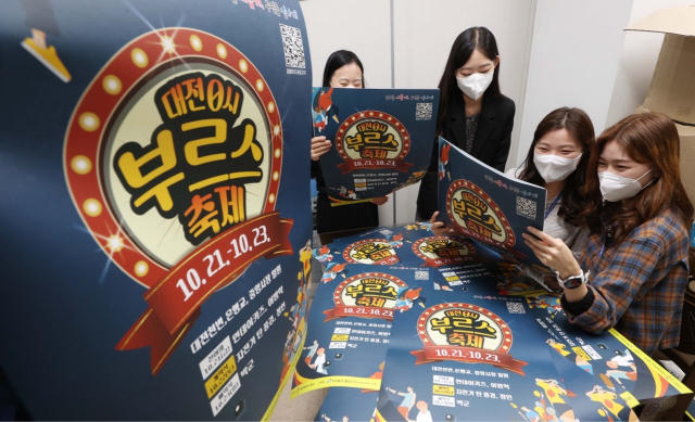동구청 직원들이 ‘대전 0시 부르스 축제 포스터를 확인 하고 있다. 사진제공=대전 동구청