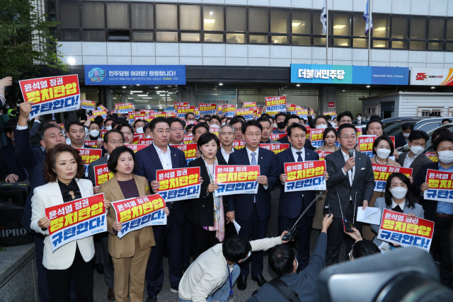 더불어민주당 의원들이 19일 서울 여의도 중앙당사 앞에서 검찰의 민주연구원 압수수색 시도를 규탄하는 피켓팅을 하고 있다. / 연합뉴스