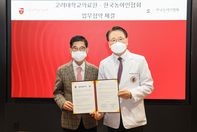 (왼쪽부터) 한국농아인협회 변승일 중앙회장과 고려대의료원 김영훈 의무부총장이 협약서에 서명 후 기념촬영을 하고있다. 사진 제공=고려대의료원