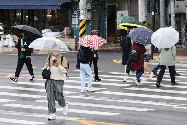 시민들이 지난 10일 오후 서울 성북구 고려대학교 안암캠퍼스 인근에서 갑자기 내린 비에 우산이나 모자를 쓰고 길을 건너고 있다. 연합뉴스
