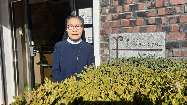 이희윤 수녀가 ‘한 사람은 온 세상보다 소중하다’는 착한목자수녀회 정신이 새겨진 표지석 앞에서 포즈를 취하고 있다.