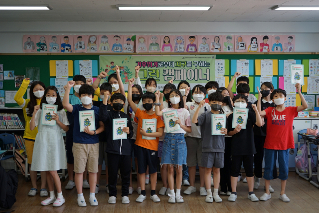 ‘2022 한화토탈에너지스와 함께하는 에코더하기 그린 캠페이너’에 참가한 서울 정릉초등학교 학생들이 책자를 들고 사진촬영을 하고 있다. 사진제공=한화토탈에너지스
