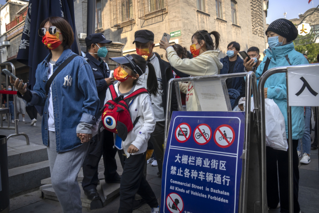 중국 베이징의 한 쇼핑가에서 마스크를 쓴 시민들이 7일 코로나19 관련 스마트폰 앱을 보여주고 게이트를 통과하고 있다. AP연합뉴스