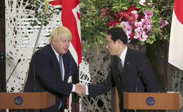 기시다 후미오(오른쪽) 일본 총리와 보리스 존슨 전 총리가 지난 5월 영국 런던에서 정상 회담을 한 이후 열린 공동 기자회견에서 서로 악수하고 있다. AP연합뉴스