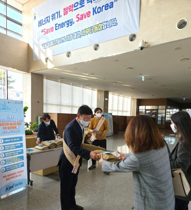 정동희 전력거래소 이사장이 지난 8일 출근하는 직원들에게 무릎담요와 에너지절약 실천 안내문을 배부하고 있다. 사진 제공=전력거래소