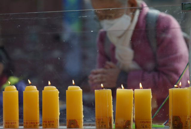 한 불교 신자가 8일 서울 종로구 조계사를 찾아 '수능대박 기원초' 앞에서 기도를 하고 있다. 연합뉴스