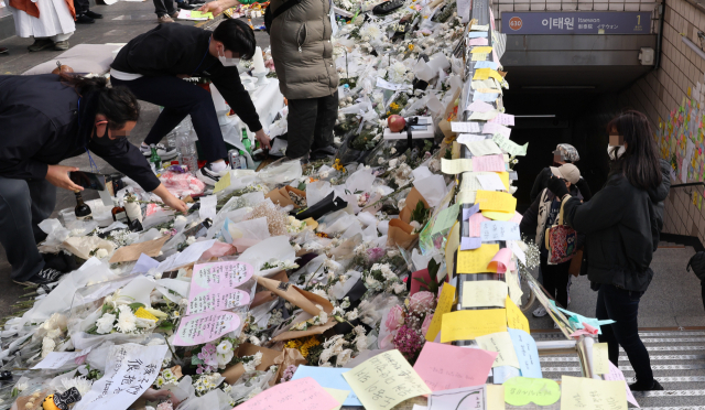 7일 이태원 참사 희생자 추모공간인 이태원역 1번 출구에서 자원봉사자들이 꽃을 정리하고 있다. 연합뉴스