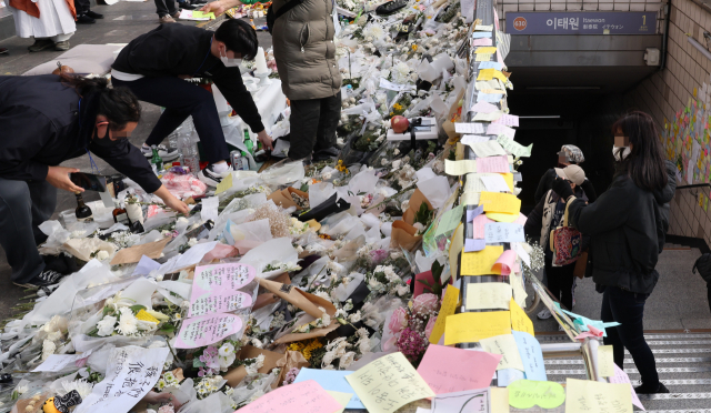 자원봉사자들이 지난 7일 이태원 참사 희생자 추모공간인 이태원역 1번 출구에서 시민들이 놓고 간 꽃을 정리하고 있다. 연합뉴스