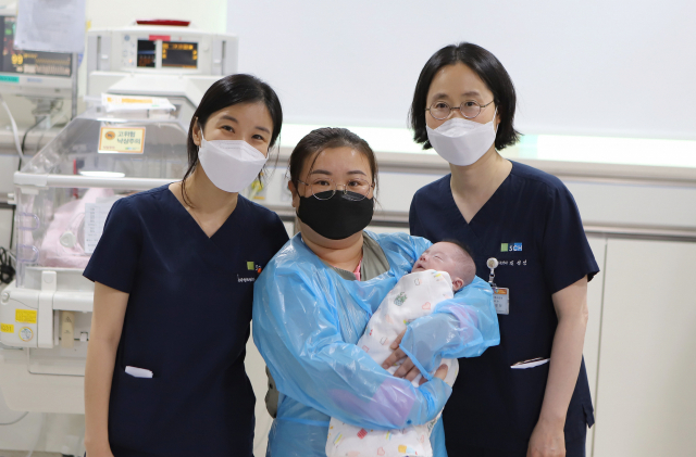 박가영(왼쪽) 소아청소년과 교수, ‘초극소 미숙아’ 진기태 군와 어머니(가운데), 김성신 신생아집중치료지역센터장이 기념 촬영을 하고 있다. 사진 제공=순천향대 부천병원