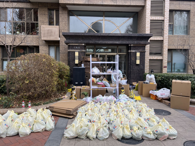 방역 요원들이 22일 베이징 차오양구에 봉쇄 중인 한 아파트 주민들에게 나눠줄 식료품을 정리하고 있다. 김광수특파원