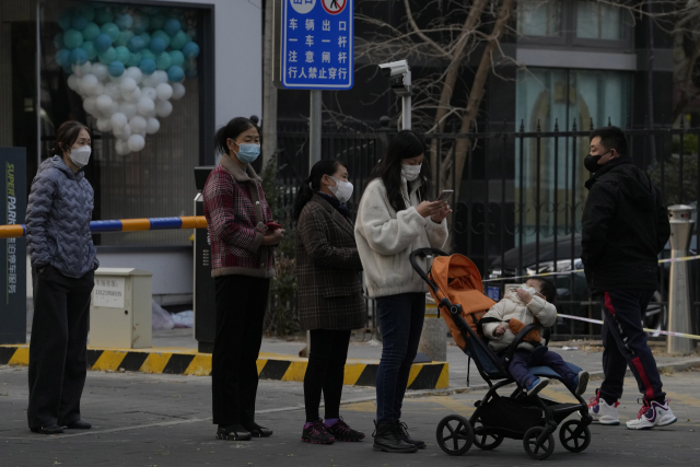 마스크를 쓴 베이징 주민들이 23일 코로나19 검사를 받기 위해 줄을 서 있다. AP연합.